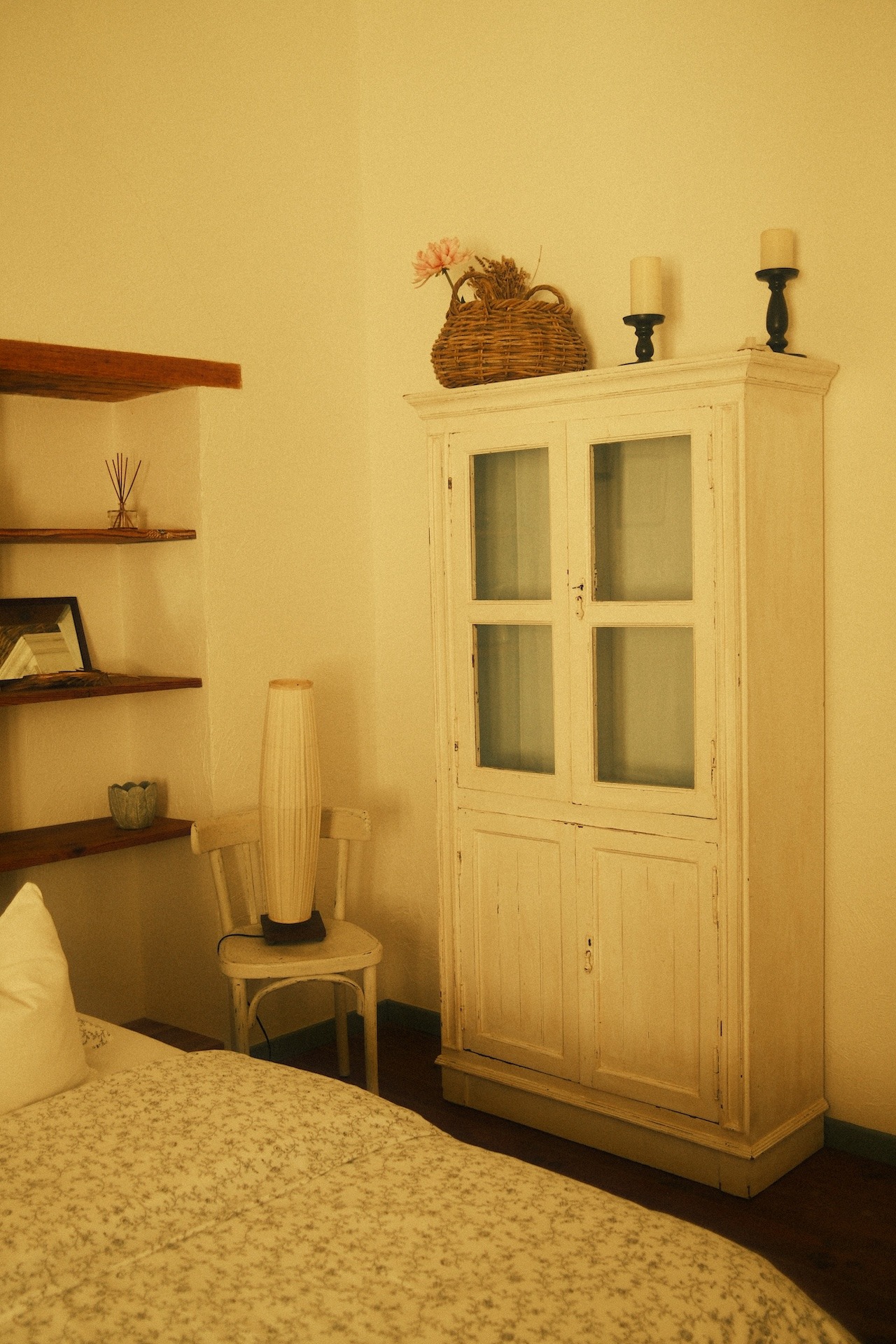 Quiet guest room corner with a glass cabinet and shelves