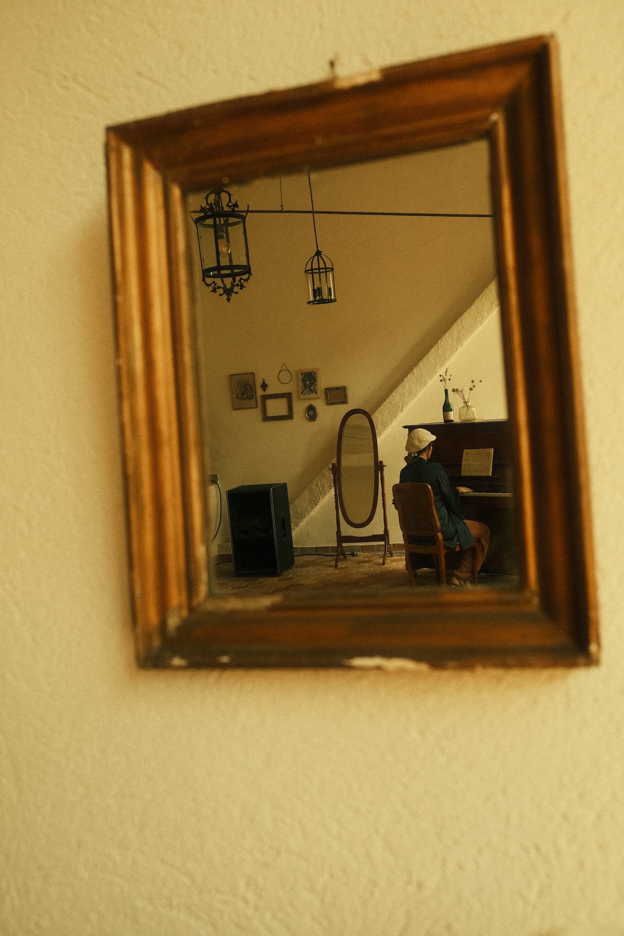 A participant playing piano, reflected in a large gilded mirror