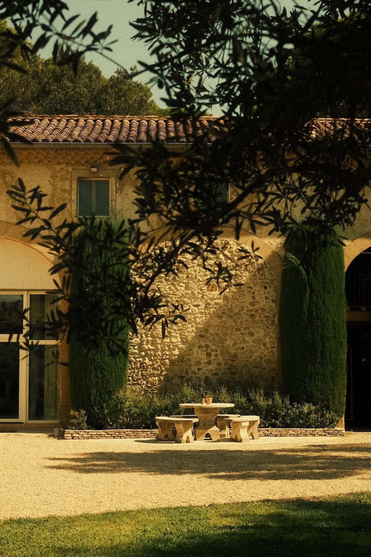 Stone facade of the farmhouse with climbing plants and cypress trees