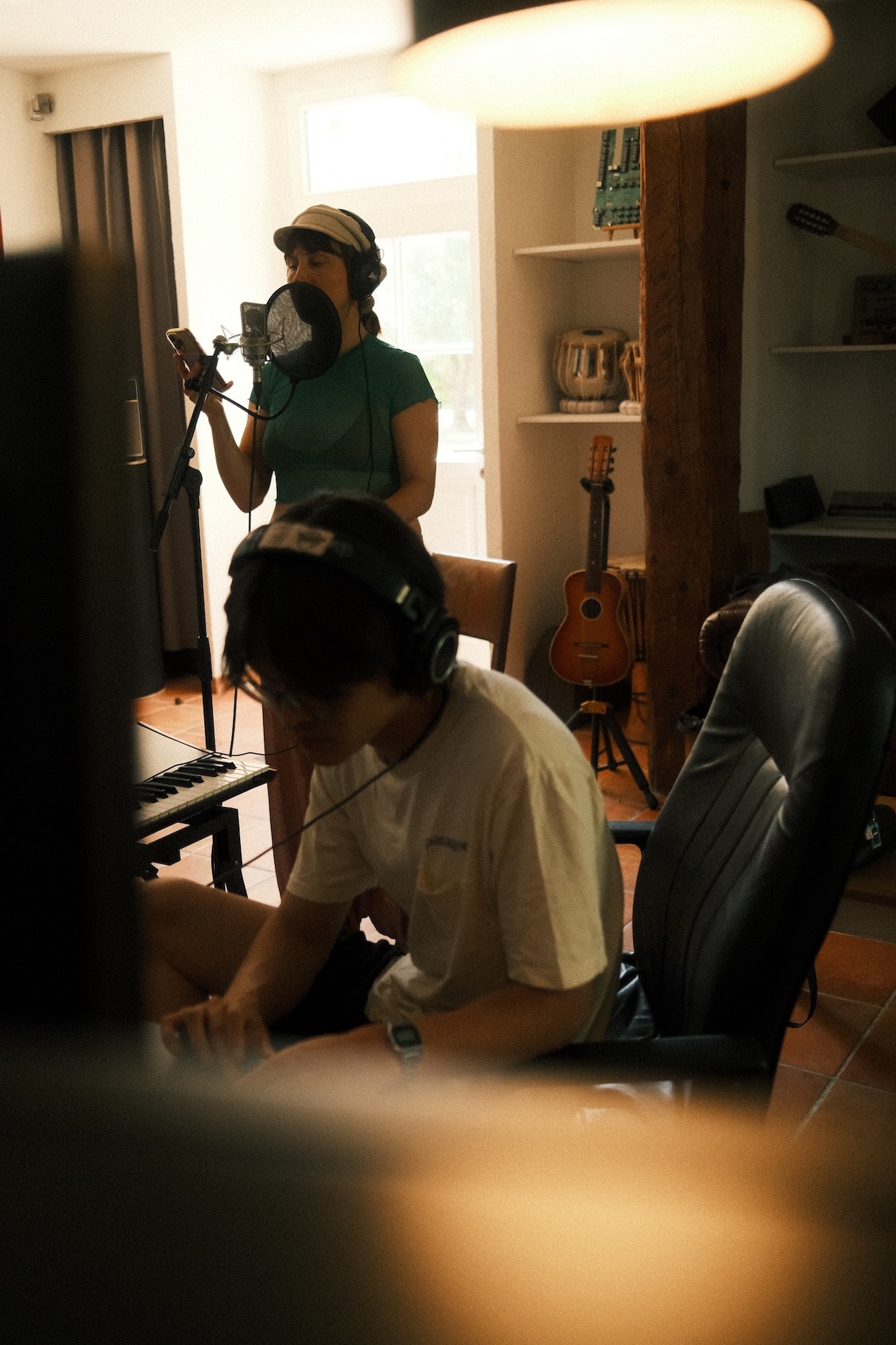 A musician playing keys while wearing headphones in the studio