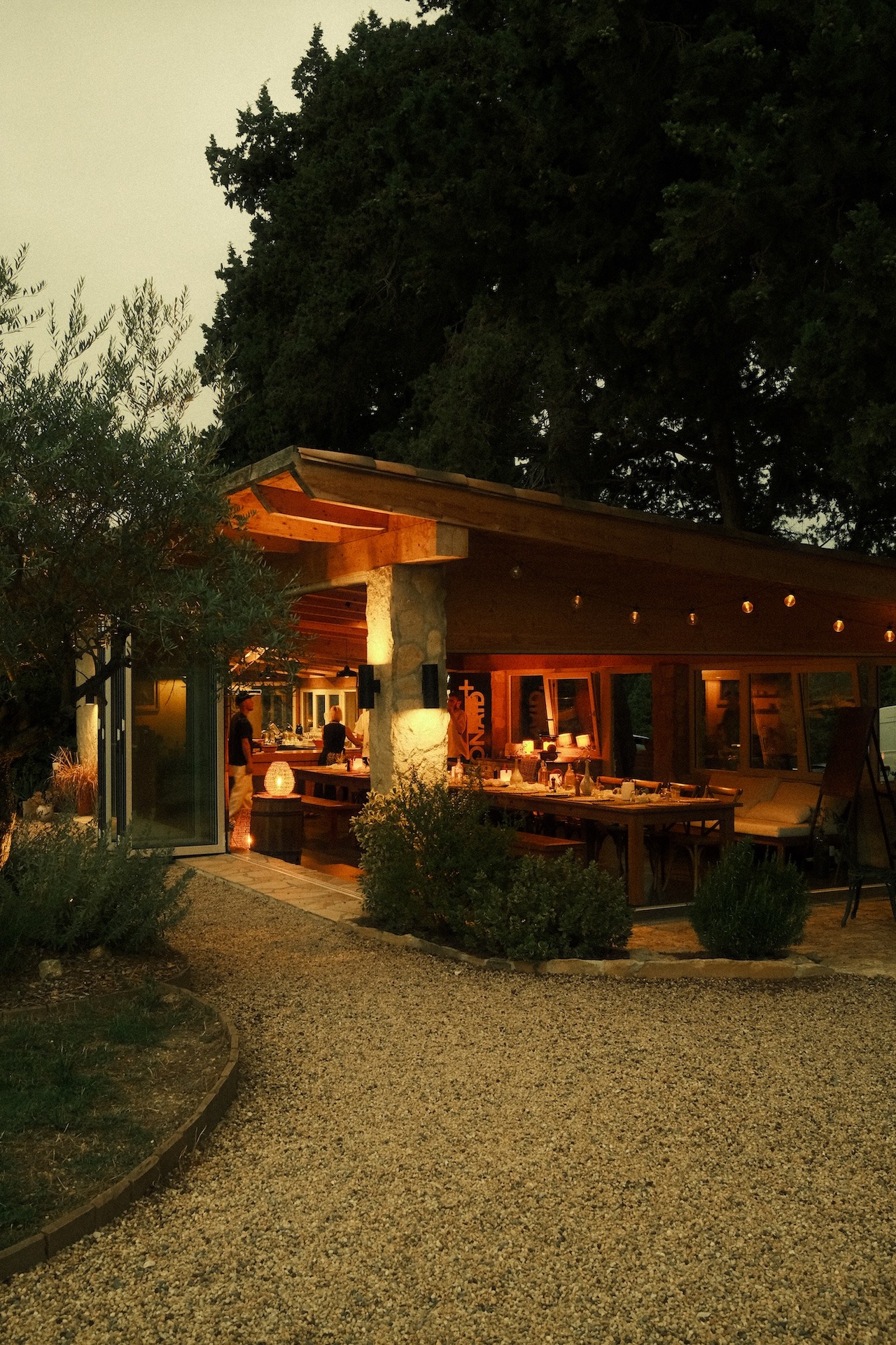 The farmhouse lit up at dusk with the dining area and string lights